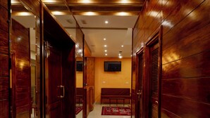A hallway with wooden paneling, a bench, and a television mounted on the wall.