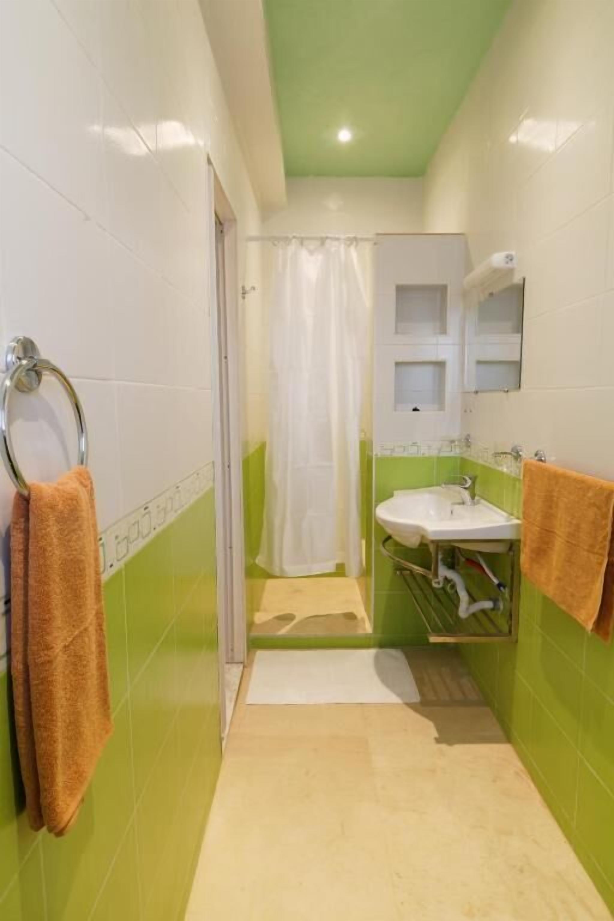 Une petite salle de bain avec une douche, un lavabo et un miroir.