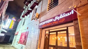 A hotel entrance with a reception desk, a signboard, and a cobblestone street.