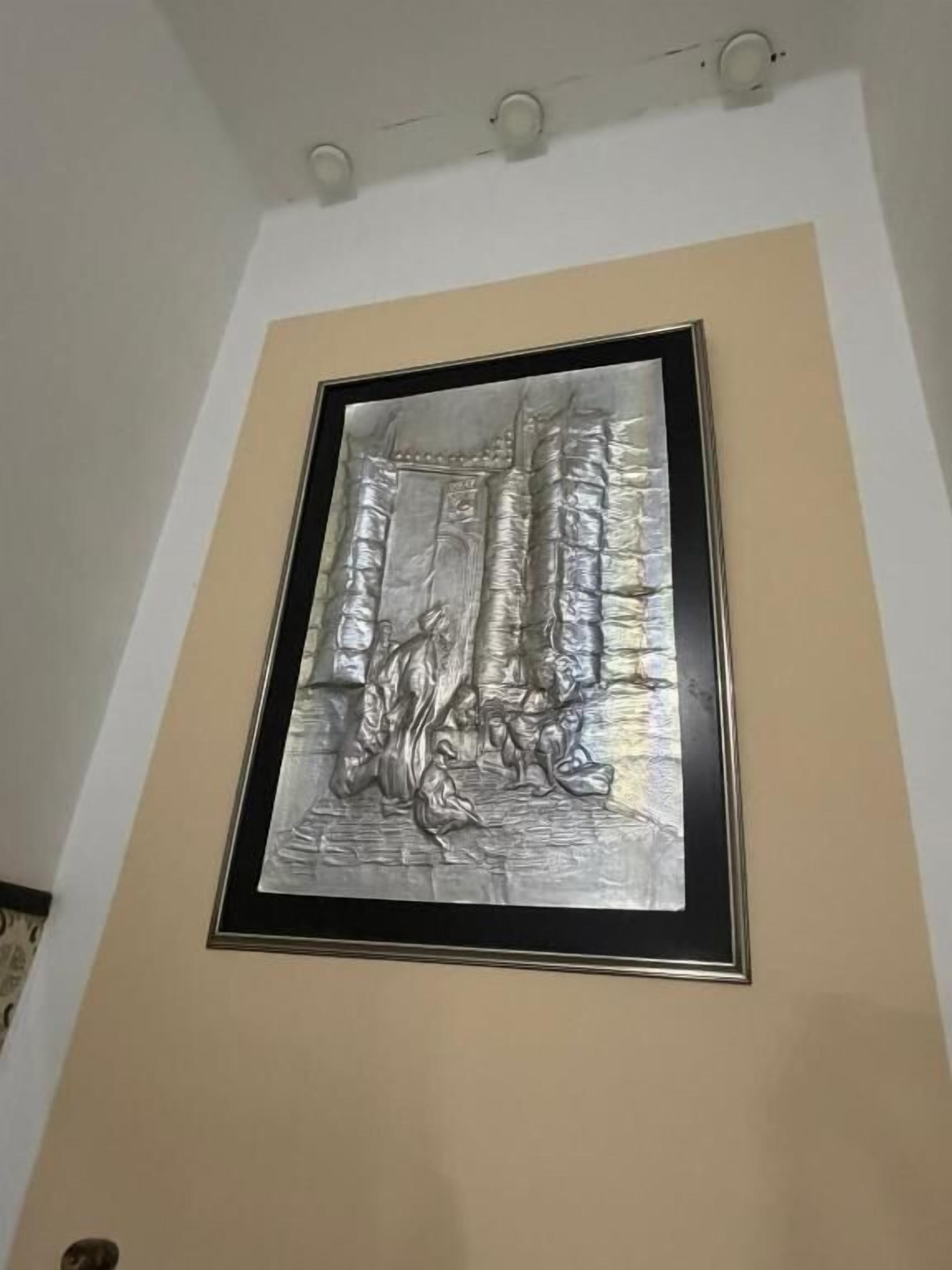 Uma obra de arte metálica emoldurada numa parede.
