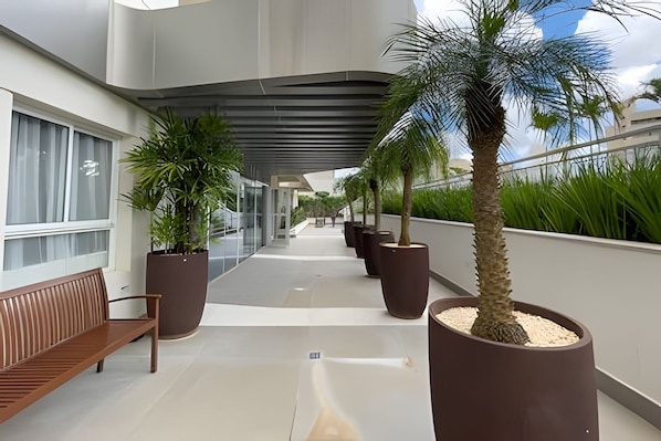 Un pasillo con bancos, plantas en macetas y un diseño arquitectónico moderno.