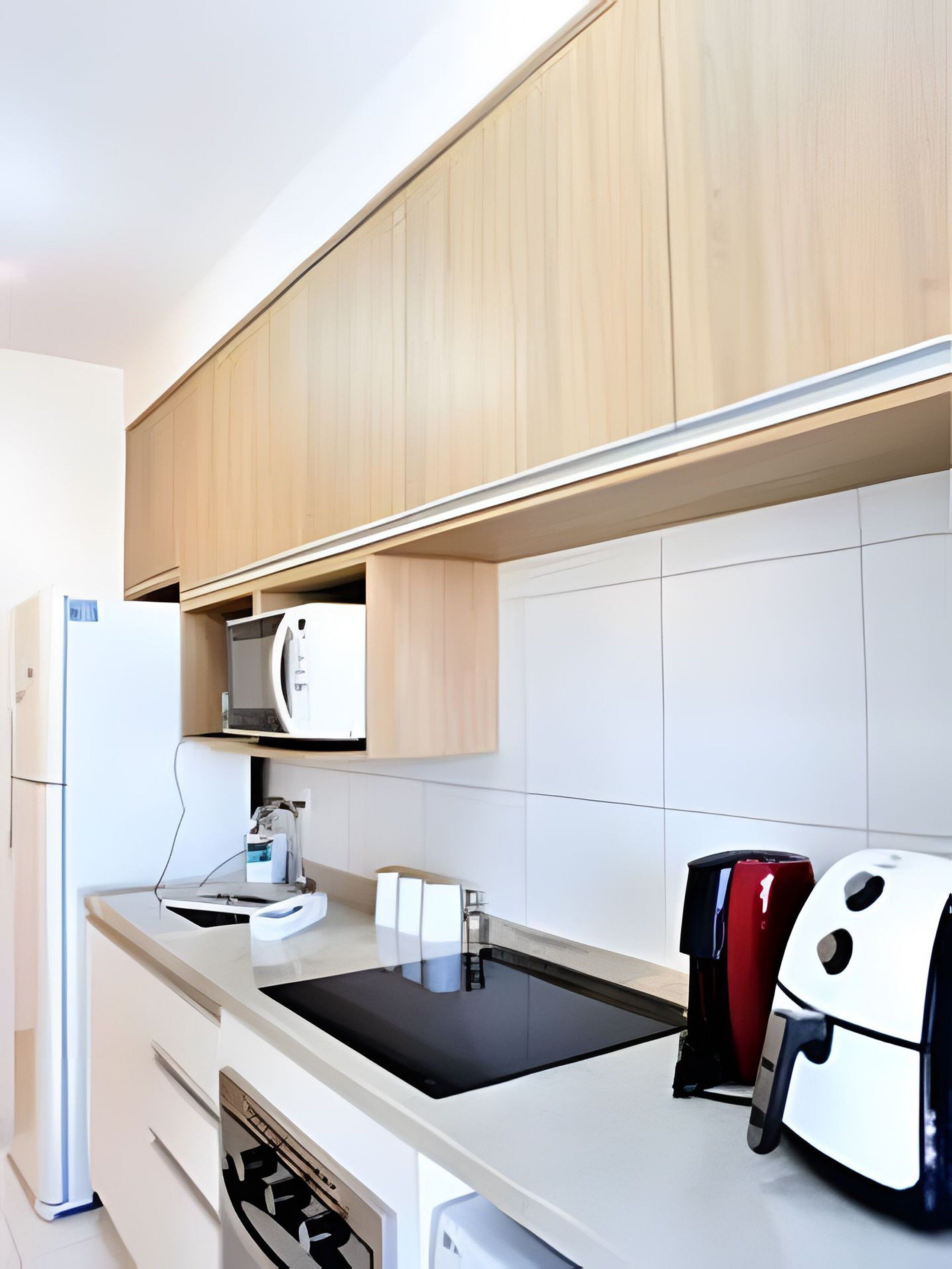 A modern kitchen with wooden cabinets, a microwave, a coffee machine, a sink, and a toaster.