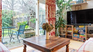 Una sala de estar con una mesa de centro de madera, un televisor y una estantería llena de juegos de mesa.