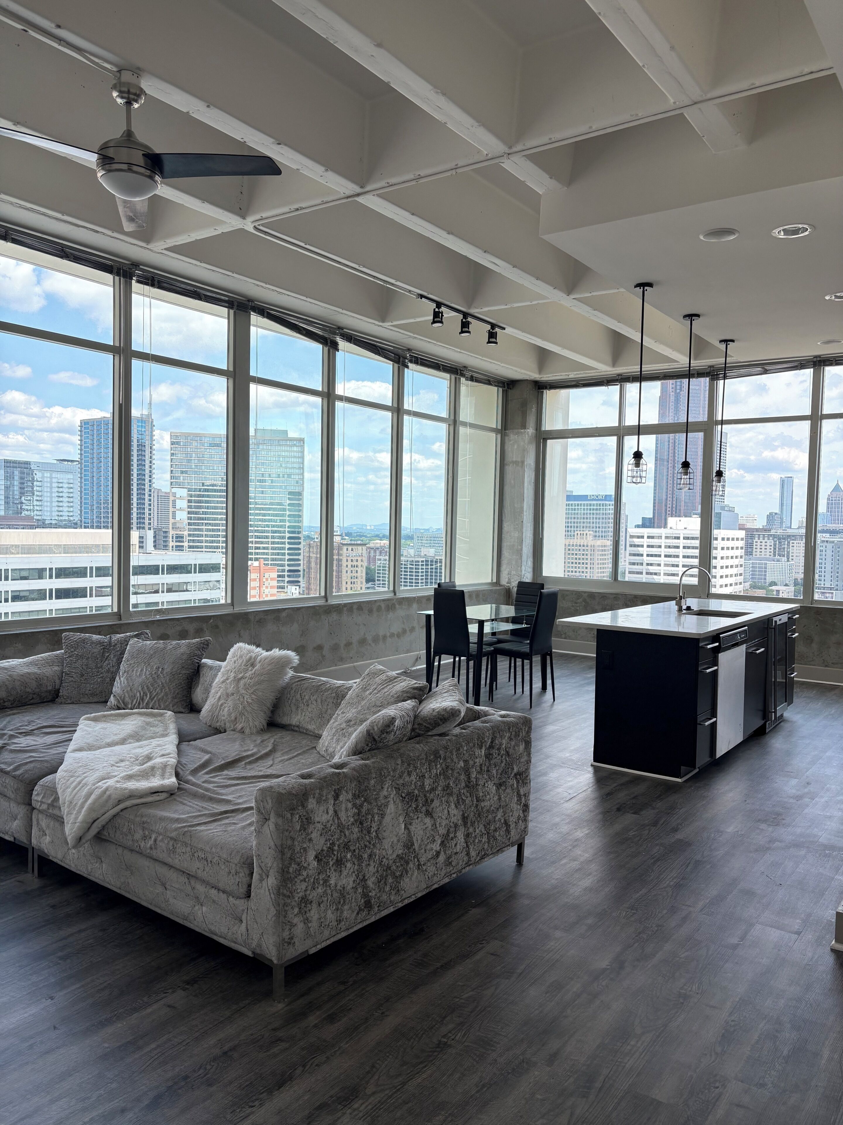A modern living room with a large sofa, a dining area, and a kitchen island.