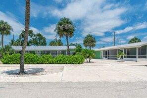 A building with a green facade, a parking lot, and palm trees. - 🏖️ Dune Your Thing D | Fort Myers Beach Villa | Pool + Near Times Square (Fort Myers Beach)