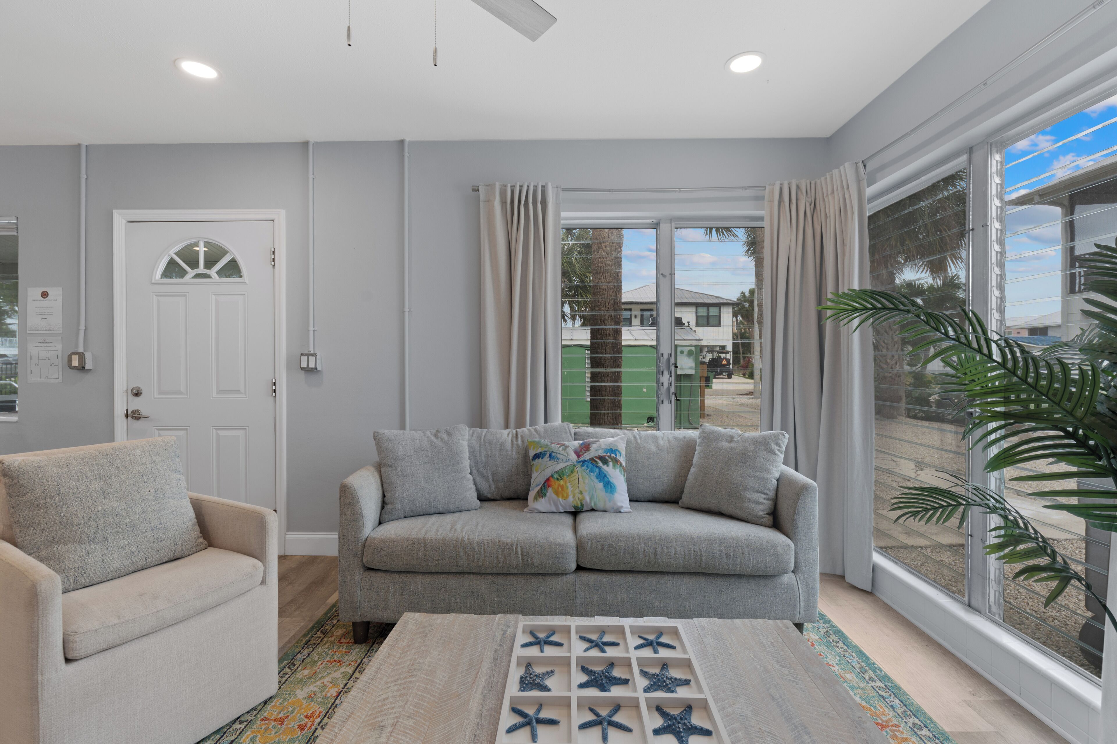 A living room with a sofa, a coffee table, and a large window with curtains.