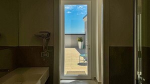 Une salle de bain équipée d’une douche, d’un lavabo et d’un sèche-cheveux fixé au mur.