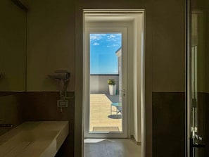 A bathroom with a shower, a sink, and a hairdryer on the wall.