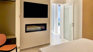 Une chambre d’hôtel équipée d’un lit, d’un téléviseur à écran plat, d’une petite fenêtre, d’une chaise et d’une porte donnant sur un balcon.