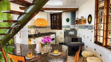 A kitchen with a dining area, wooden staircase, and a view of the outdoors.