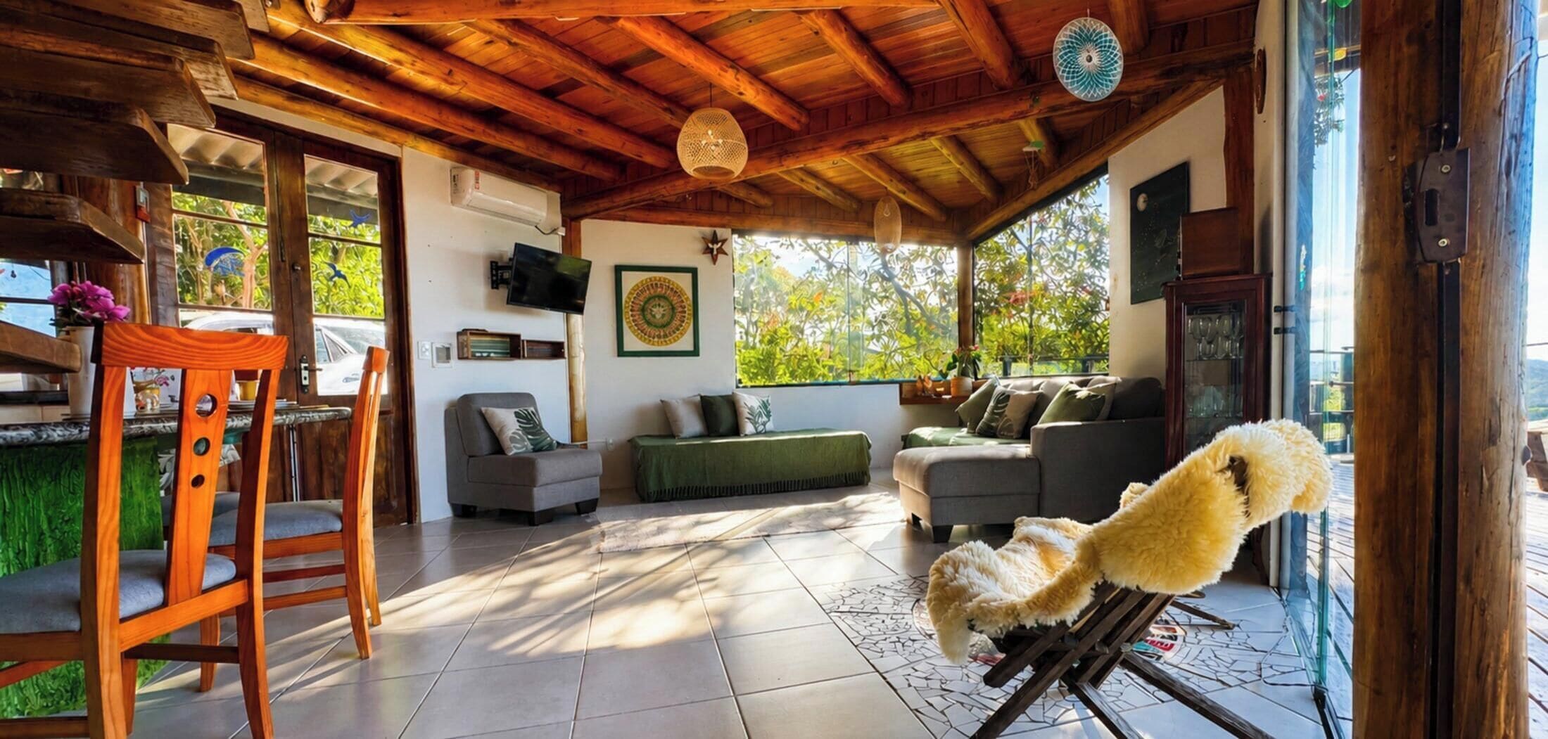 Un espacio exterior techado con techo de madera, un sofá, una silla y una mesa.