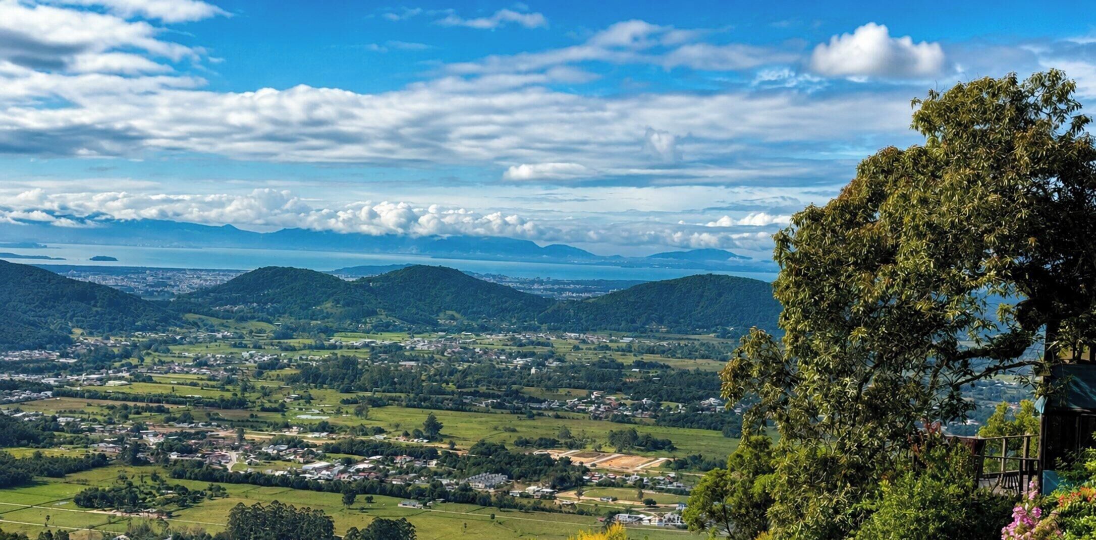 Une vue panoramique d’une vallée avec une ville, des montagnes et une étendue d’eau.