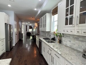 A kitchen with white cabinets, a stainless steel refrigerator, a granite countertop, and a hanging light fixture. - Large DC Home for Families & Groups - Free Parking - Prime Location (Washington)
