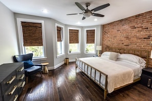 A bedroom with a bed, a chair, a dresser, and a brick wall. - Large DC Home for Families & Groups - Free Parking - Prime Location (Washington)