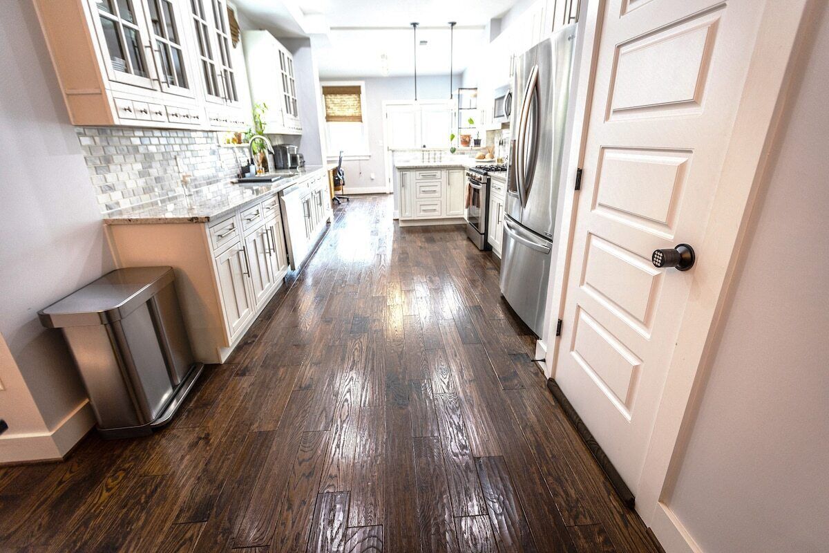 A kitchen with white cabinets, stainless steel appliances, and a wooden floor.