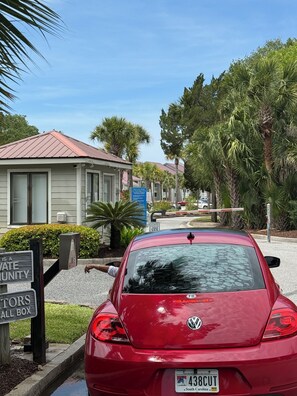 Punainen Volkswagen oli pysäköitynä rakennuksen eteen, ja rakennuksessa oli metallikatto. Sen ympärillä kasvoi palmuja, ja lähellä oli kyltti, josta kävi ilmi, että kyseessä oli yksityinen asuinalue.