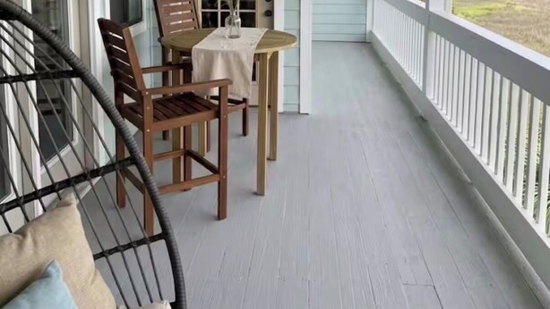 Eine Veranda mit Deckenventilator, Tisch und Stühlen sowie Blick auf den Ozean.