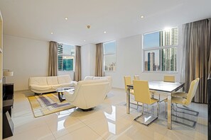 A modern living room with a sofa, a coffee table, and a dining area with chairs and a table. - Prime 3Bed APT Near Dubai Canal & Burj Khalifa (Dubai)