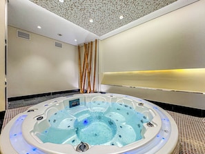 Ein modernes Badezimmer mit einer großen, runden, freistehenden Badewanne, einer Decke mit einem Muster und einem wandmontierten Waschtisch.