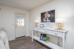 Een witte console tafel met een lijst, twee lampen en een klein plantje.