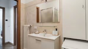 Un baño con un lavamanos blanco, espejo y electrodoméstico blanco de LG.