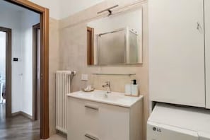 Ein Badezimmer mit einem weißen Waschbecken, einem Spiegel und einem weißen LG-Gerät.