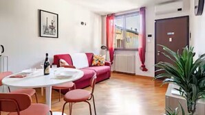 Una habitación con una mesa de comedor, sillas, un sofá, un radiador, una puerta y una planta.