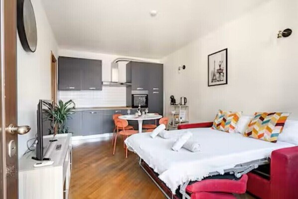 Ein Schlafzimmer mit einem Bett, einem Schreibtisch, einem Stuhl und einer kleinen Küchenzeile.