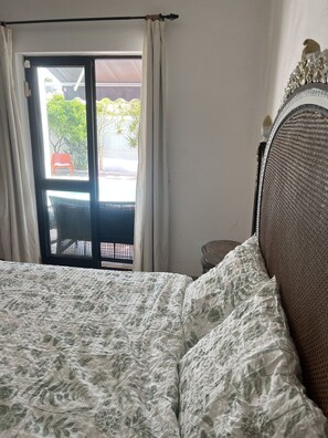 Ein Schlafzimmer mit Bett, einem fenster mit Vorhängen und Blick ins Freie.
