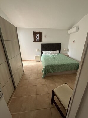 A bedroom with a bed, a nightstand, a chair, and a wall-mounted air conditioner. - Private Pool • 8-Min Walk to Praia da Oura Beach • Prime Albufeira Location (Albufeira)