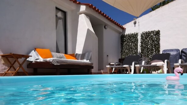 A swimming pool with lounge chairs and a flamingo float. - Private Pool • 8-Min Walk to Praia da Oura Beach • Prime Albufeira Location (Albufeira)