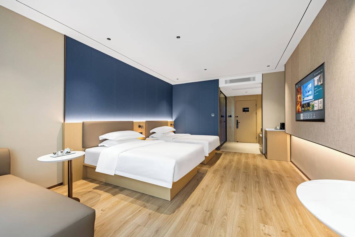Una habitación de hotel moderna con una cama grande, mesitas de noche, un televisor y un baño.