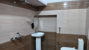 A bathroom with a white sink, a toilet, and a shower area. - Amrit Niwas (Ayodhya)