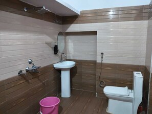 A bathroom with a white sink, a toilet, and a shower area. - Amrit Niwas (Ayodhya)