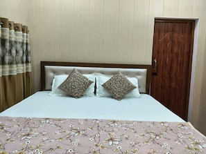 Ein Bett mit blumigem Überwurf, zwei gemusterten Kissen und einem hölzernen Kopfteil.