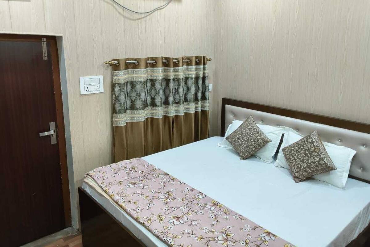Une chambre à coucher avec un lit, des rideaux, une porte et une prise électrique.