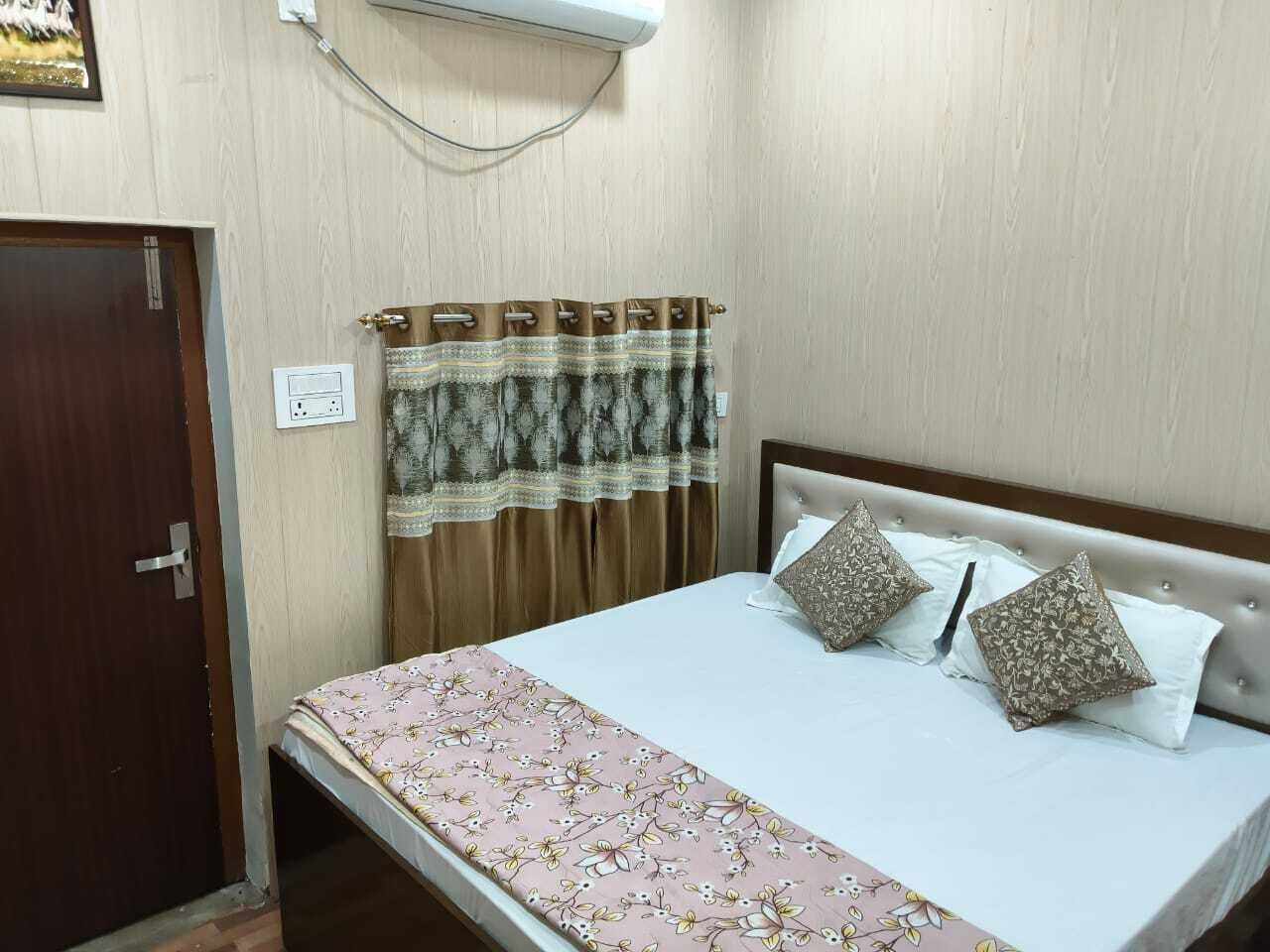 Ein Schlafzimmer mit Bett, Vorhängen, einer Tür und einer Steckdose.