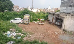 A residential area with a white car, a rickshaw, and a building with a concrete facade. - Amrit Niwas (Ayodhya)