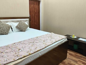 Ein Schlafzimmer mit einem Bett, Kissen, einem Nachttisch und einer Mülltonne.