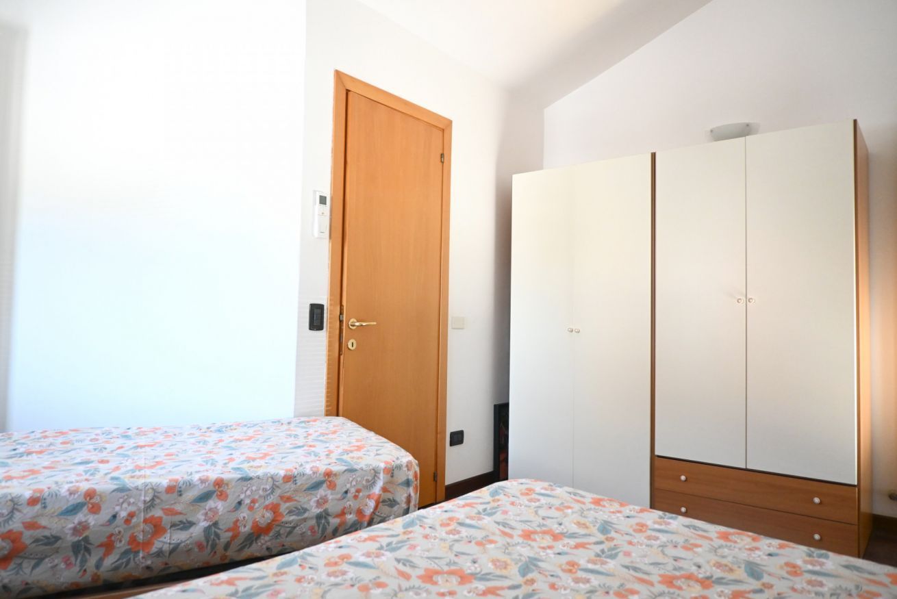 Een slaapkamer met twee bedden, een kledingkast en een deur.