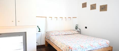 Un dormitorio con cama, escritorio y ventana.