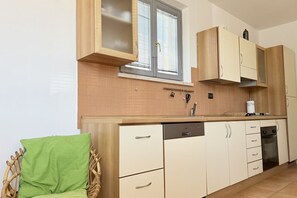 A kitchen with wooden cabinets, a dishwasher, a stove, and a window with blinds. - SE288 – Senigallia, one-bedroom apartment with air conditioning 50 metres from the sea (Senigallia)
