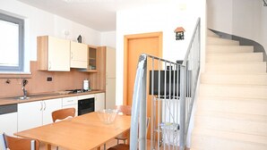 Una cocina con una mesa de comedor, sillas y una escalera.