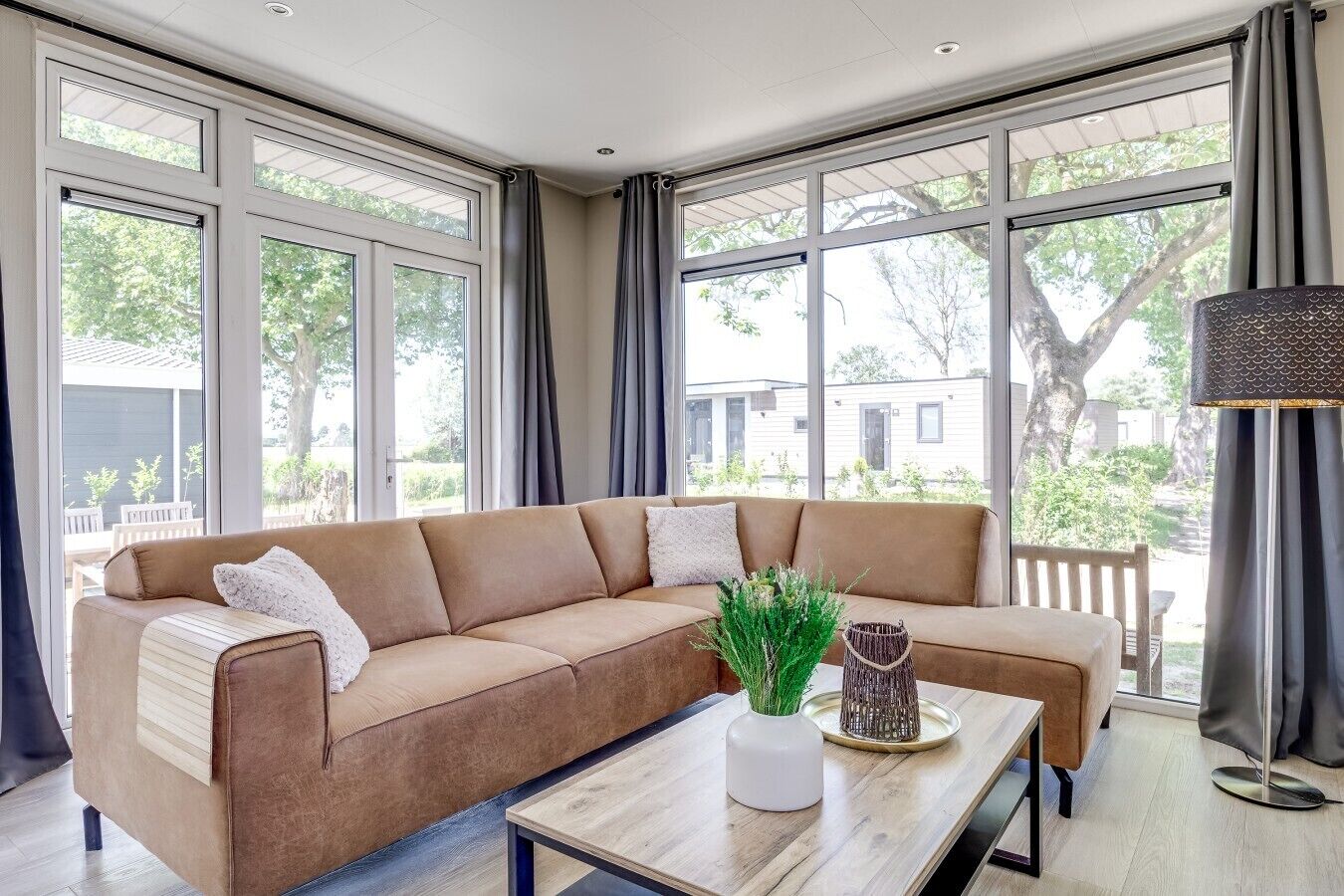 Una sala moderna con un sofá modular, una mesa de centro y ventanas amplias con vistas al exterior.