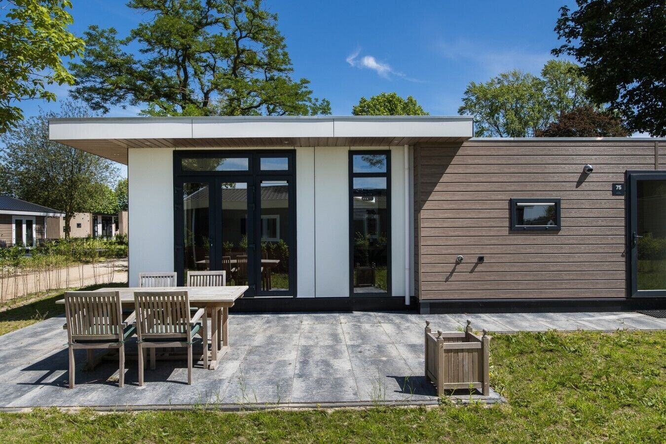Un bâtiment moderne doté d’un patio couvert, d’un coin repas avec des chaises et d’une petite fenêtre.