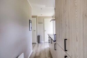A hallway with a wooden wardrobe, a glass shelf, and a door leading to another room.