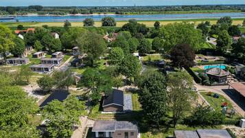 A residential area with houses, a swimming pool, and a river in the background.