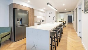 Une cuisine moderne dotée d’un grand îlot central, d’appareils électroménagers en acier inoxydable et d’un coin bar.