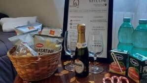 A welcome sign, a bottle of wine, glasses, a basket of snacks, and yoga boxes on a table. - Mosaico (Pompei)