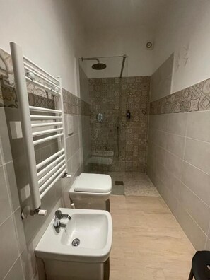 A narrow bathroom with a shower, toilet, and sink. - Mosaico (POMPEI)